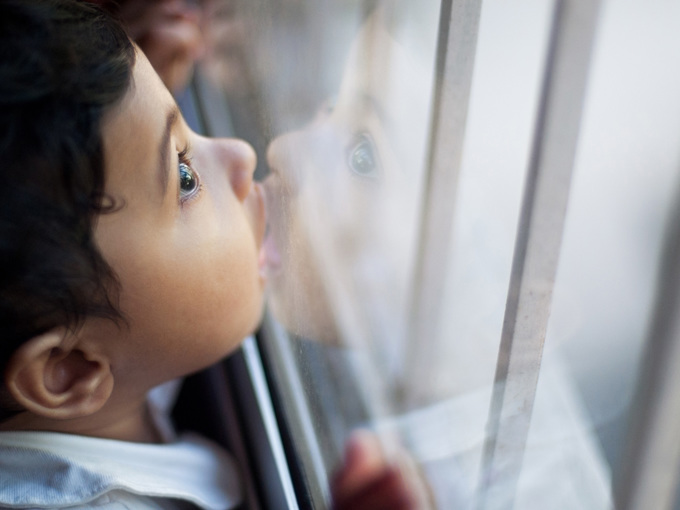 Nettes kleines Mädchen, das Glasfensterscheibe küsst