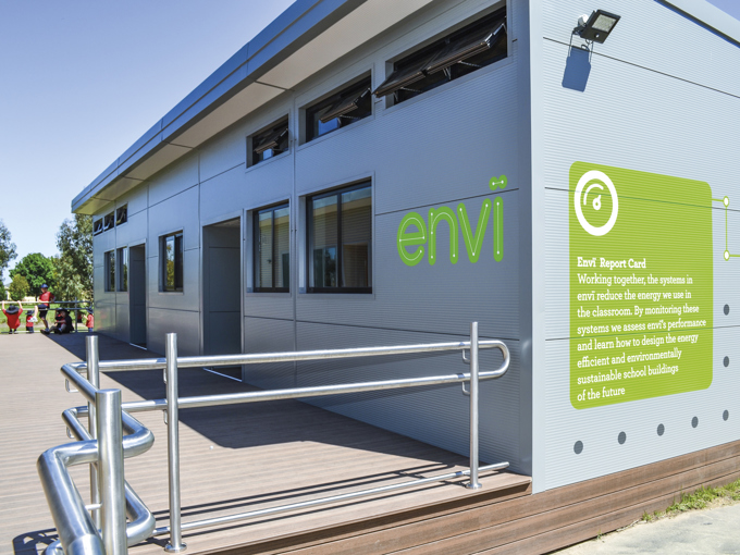 Modernes modulares Schulgebäude mit kleinen, nach außen gerichteten Fenstern an der Außenwand und einer behindertengerechten Rampe.